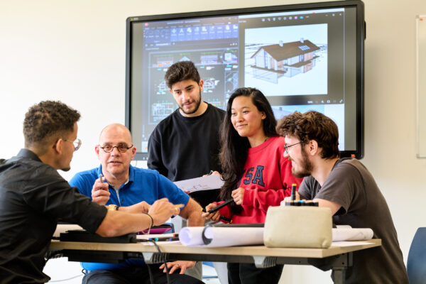 MBO-studenten Bouwkunde in gesprek met hun docent in een klaslokaal