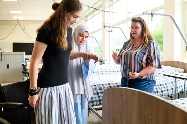 MBO-studenten zorg oefenen in begeleiden van cliënt met fysieke beperking