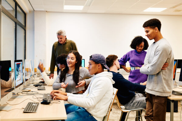 MBO-studenten marketing tijdens een praktijkles zitten achter een computer en hebben lol
