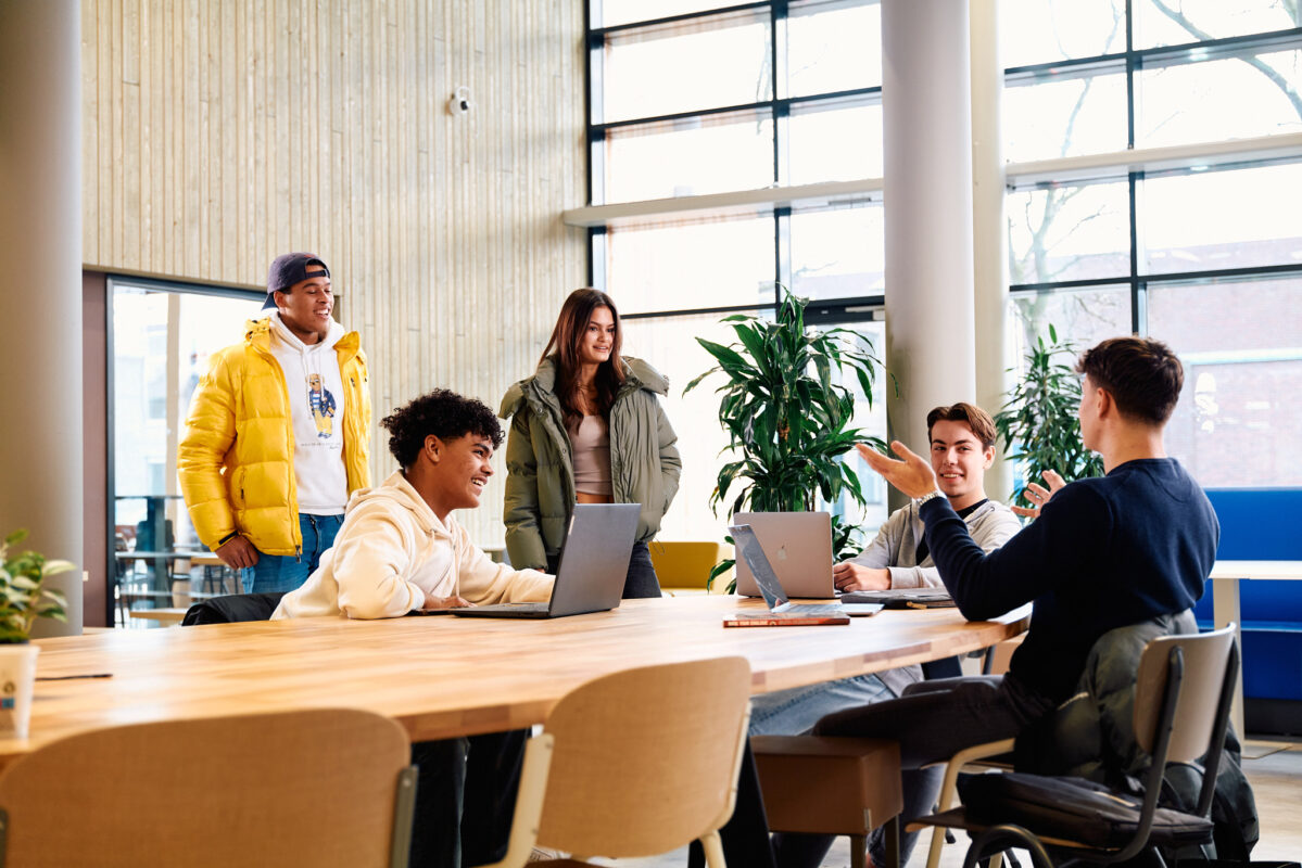 Studenten in gesprek rond een tafel in de kantine op school