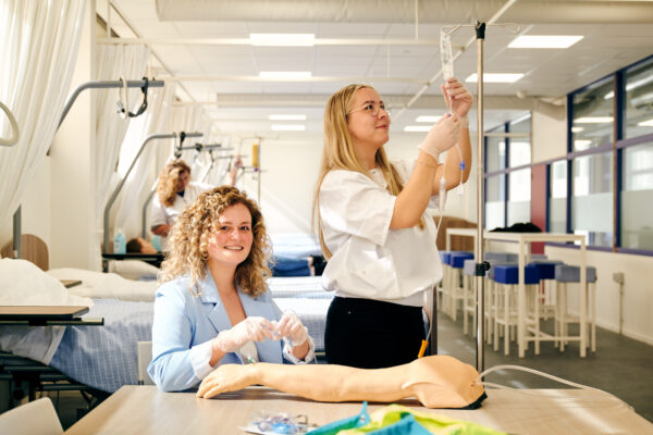 mbo-studenten zorg en welzijn oefenen met een infuus in te prikken in arm