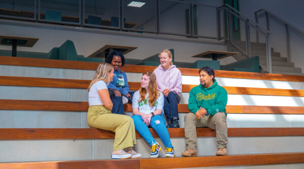 Groep studenten zitten op een trap in de entreehal van de Onderwijsboulevard