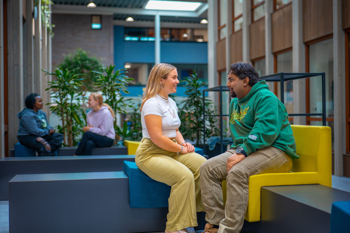 Twee groepjes mbo-studenten houden pauze in een zitje in de kantine