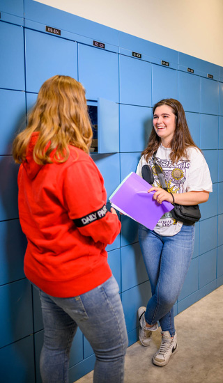Twee studenten leunen tegen hun kluisjes en zijn in gesprek